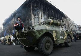 A boy poses for picture as he squats on an armoured vehicle at Independence Square in Kiev